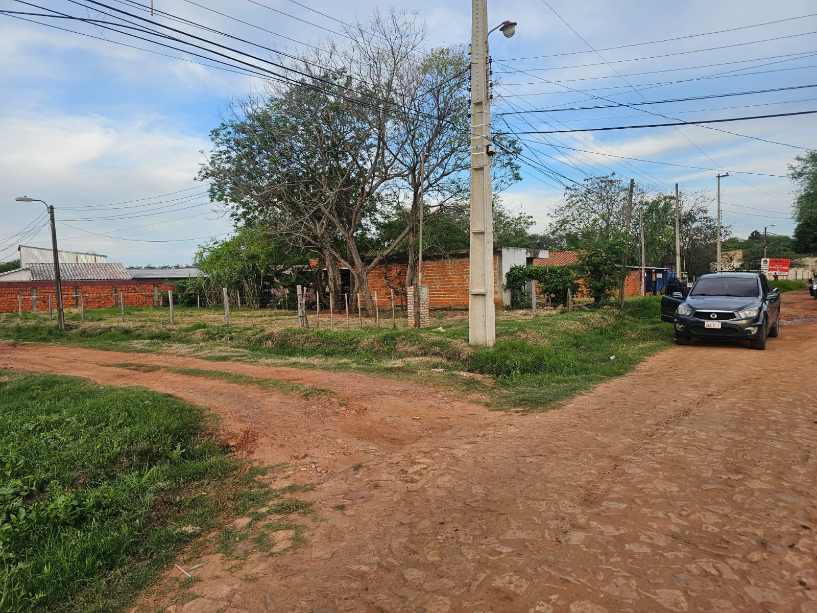 Cruce de calles de tierra frente a la esquina, con viviendas del entorno al fondo